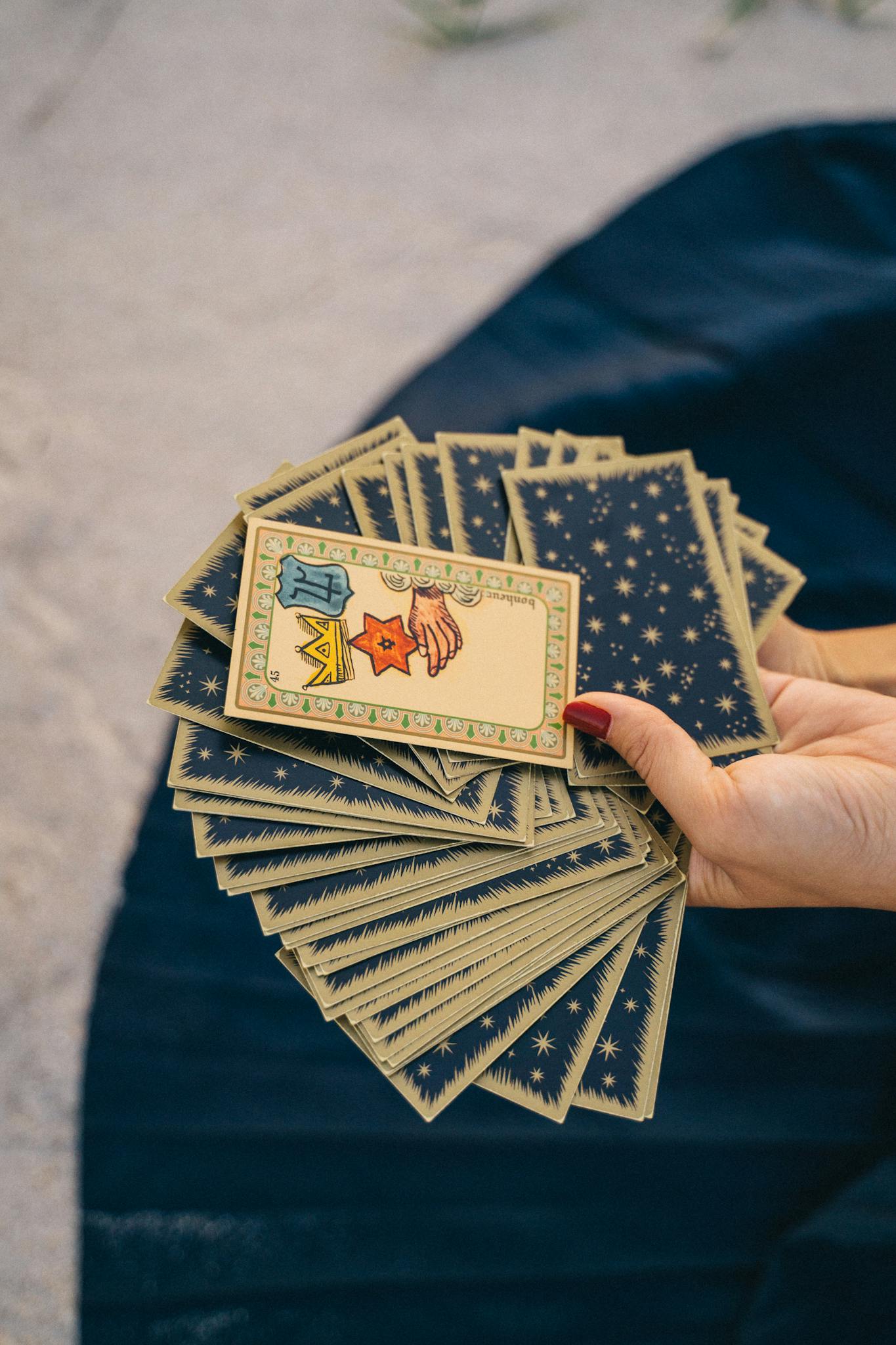 A hand holding a deck of tarot cards, symbolizing spirituality and divination.