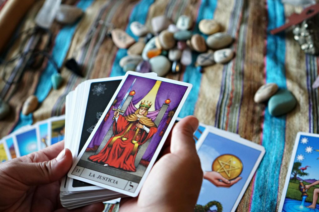 A vibrant tarot card reading scene with colorful stones and 'La Justicia' card displayed.