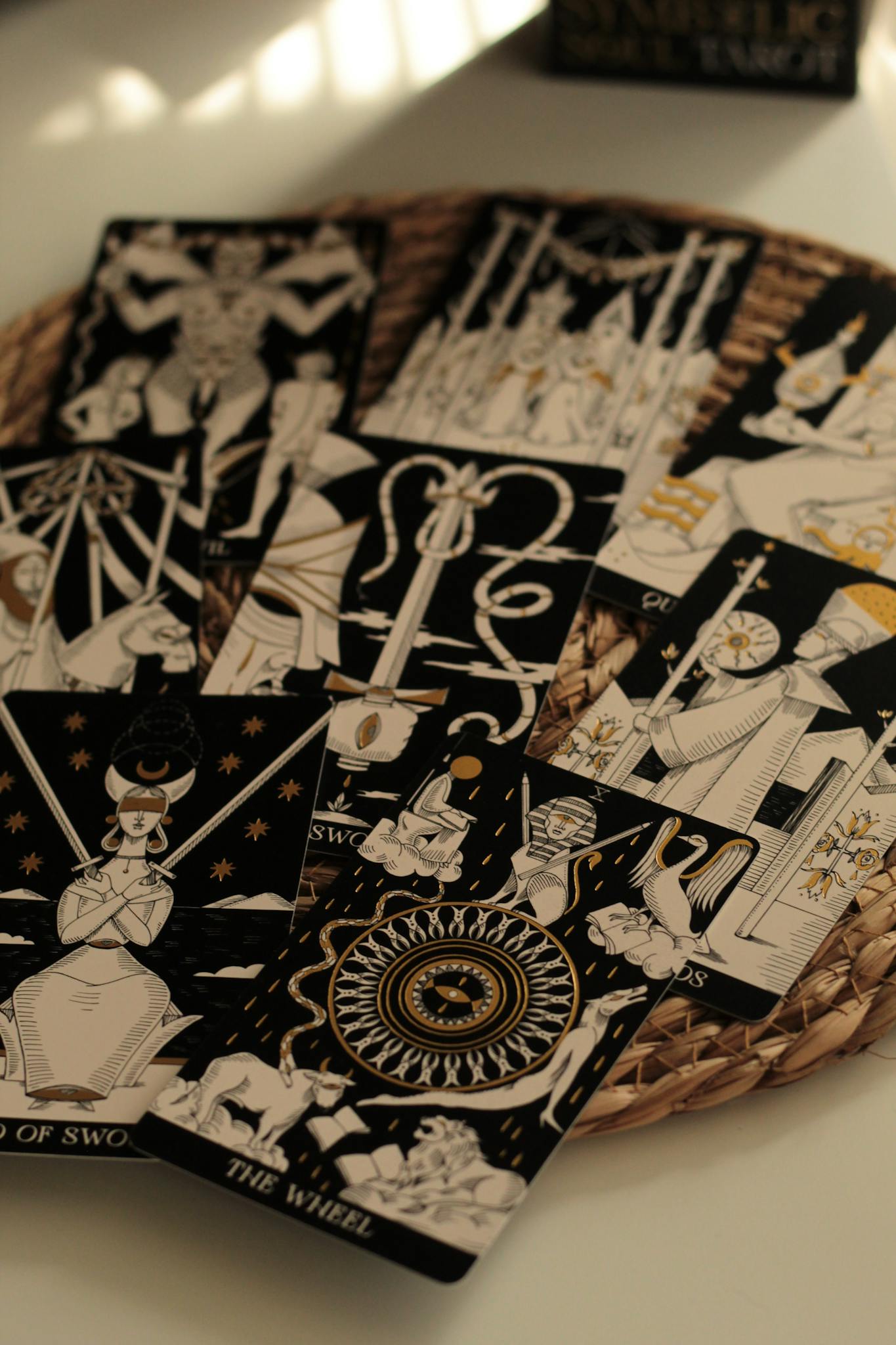Aesthetic display of tarot cards on wicker mat with soft lighting.