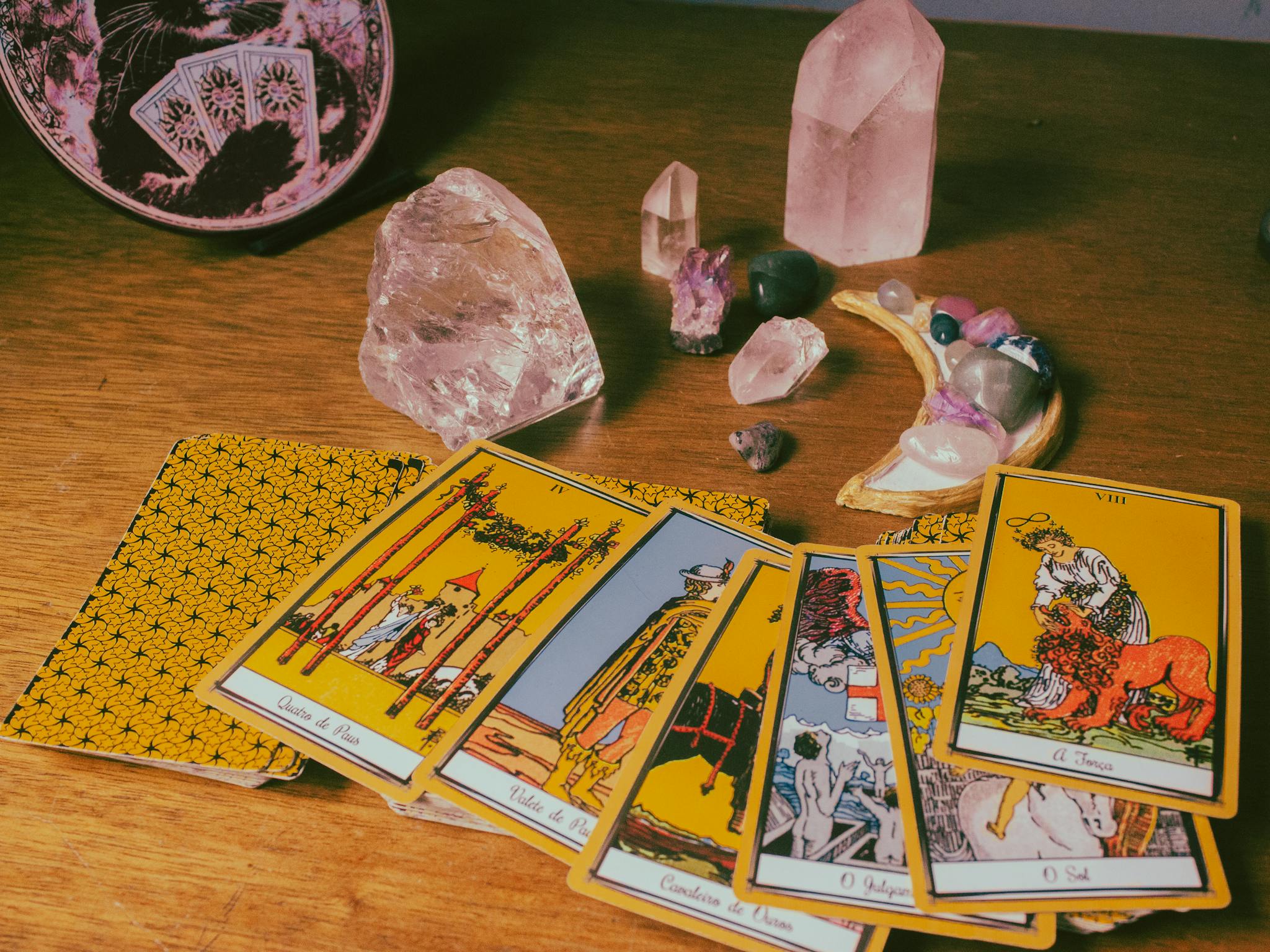 Tarot cards with crystals arranged on a wooden table, creating a mystical atmosphere.
